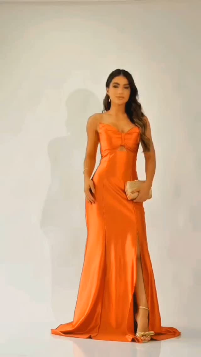 Modelo em vestido laranja longo com fenda frontal