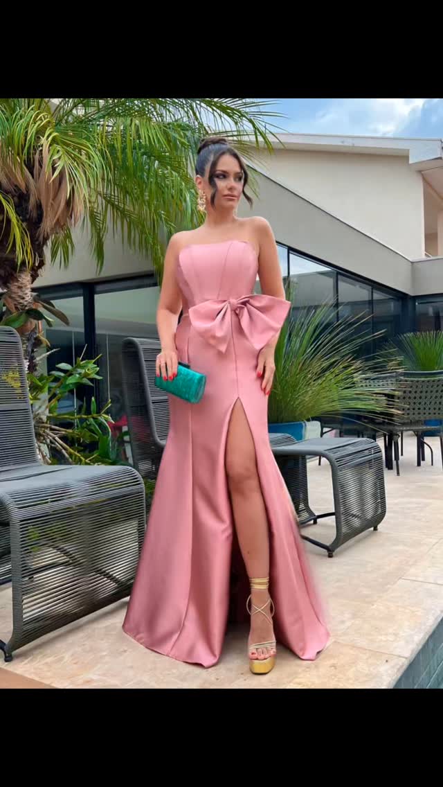 Modelo em vestido rosa-claro com laço e fenda