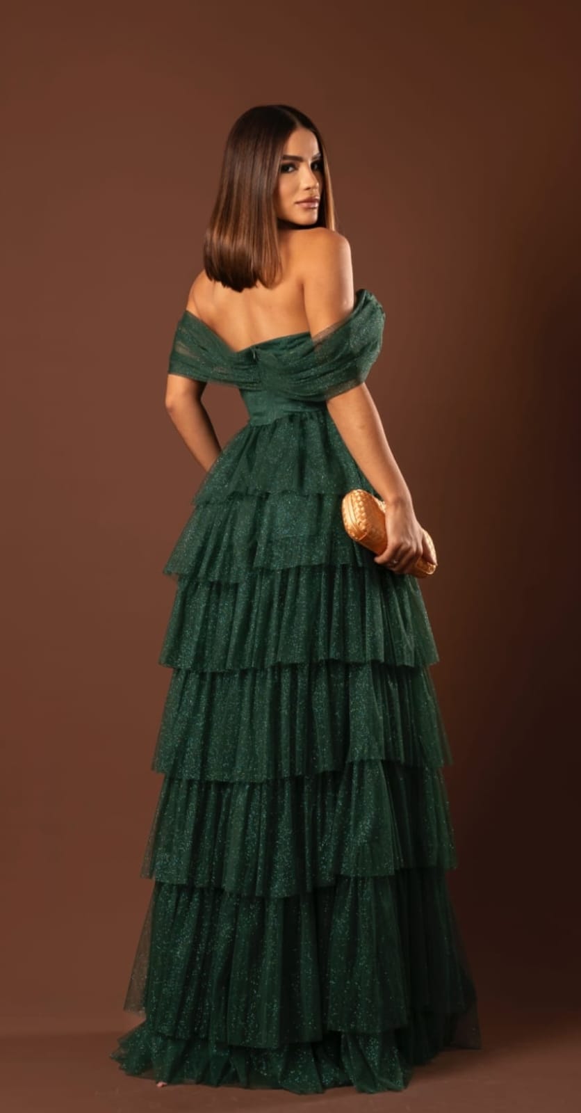 Vista lateral de vestido longo verde-esmeralda com decote ombro a ombro